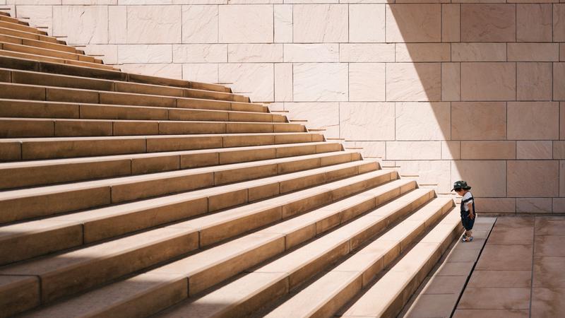 Toddler standing at the bottom of a set of concrete stairs