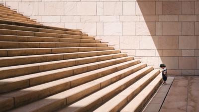 Toddler standing at the bottom of a set of concrete stairs